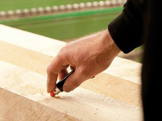 Person kennzeichnet Holz mit Stift Holzkennzeichnung durch Person für Schwörer-Holzindustrie