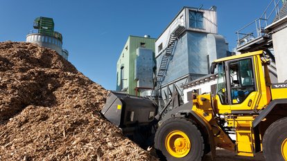 Bagger transportiert Hackschnitzel